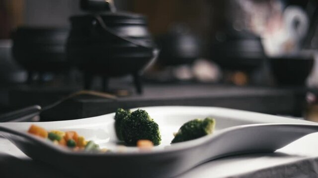 slow motion empty plate of vegetables with a few pots on a table busy cooking