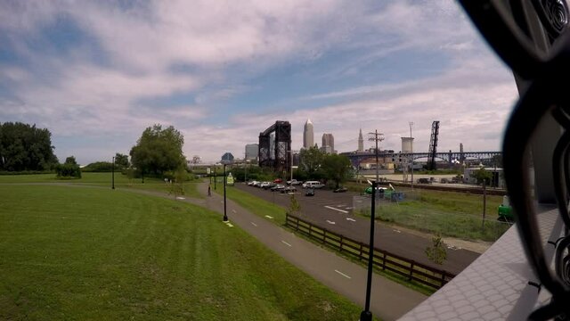 Downtown Cleveland, Ohio from the Wendy Park Whiskey Island Metroparks Bridge. Timelapse with a train going by and clouds passing on a sunny day.