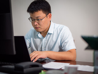 Fototapeta premium Chinese man sitting in front of office computer