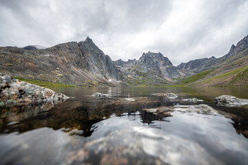 Naklejka na ściany i meble Stunning, iconic and huge Grizzly Lake viewpoint from Tombstone Territorial Park in northern Canada during summertime. Lovely, calm day with reflection of the mountains in clear, pristine water below.