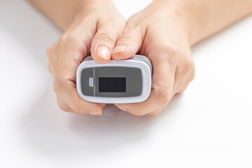 Close-up, Female hands hold the Digital Pulse Oximeter for use with measures the patient's pulse and oxygen saturation (SPO2) on white background. Healthcare concept.