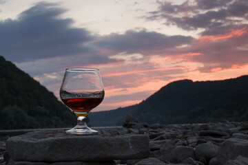 wine glass with a drink on a background of the setting sun on the river
