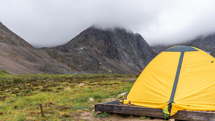 Bright yellow small two person tent in the wilderness of northern Canada on cloudy afternoon. Taken...