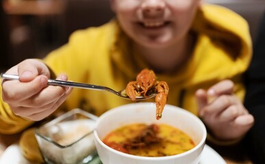 Boy eats Tom Yam soup with crayfish