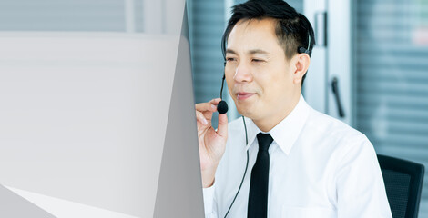 Banner candid Focus Asian handsome male callcenter smiling with headsets, sitting, monitoring, giving advice online to customers with service mind. There is copy space for message.