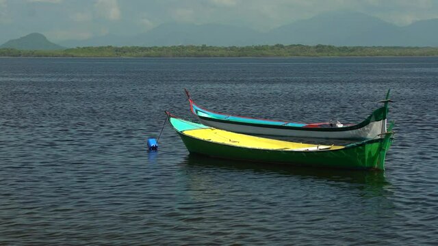 Canoas ancoradas na praia de mar tranquilo, no litoral do Paran&aacute;, Brasil.