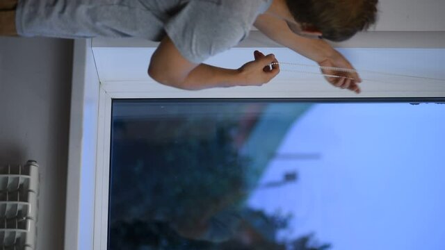 Man installing gray roller blinds on the window