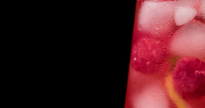 Glass of fresh raspberry lemonade on dark background, closeup