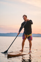 Strong man standing on a board with a paddle