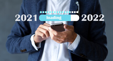 Businessman holding mobile phone with loading progress bar changing year 2021 to 2022