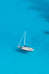 View from above, stunning aerial view of a sailboat floating on a turquoise, crystal clear water during a sunny day. Costa Smeralda, Sardinia, Italy.