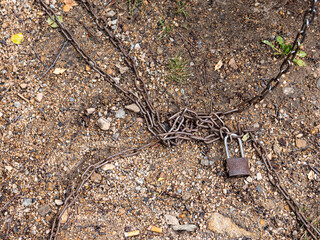 there is a rusty chain with a lock on the rocky ground