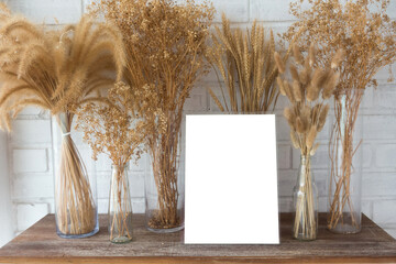 Background composition with many different dried flowers  in a glass bottle on a wooden table, Mockup white picture transparent photo frame, copy space for product display.