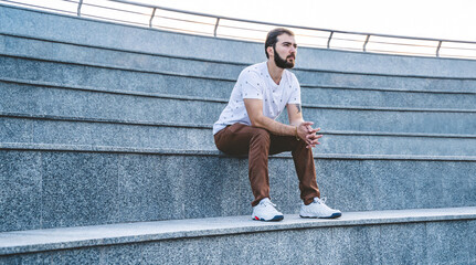 Lonely man on steps. Calm guy in casual style sits pensive