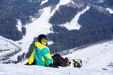 Fototapeta na wymiar man sitting with snowboard on the top of the hill with beautiful view