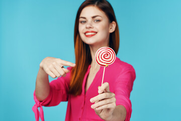 woman in pink shirt with lollipop in hands charm blue background