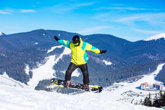 Man In Green Coat Jumping With Snowboard