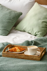 Fototapeta na wymiar Tray with cup of coffee and croissant on bed