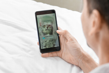 Young man with mobile phone checking his e-mail in bedroom