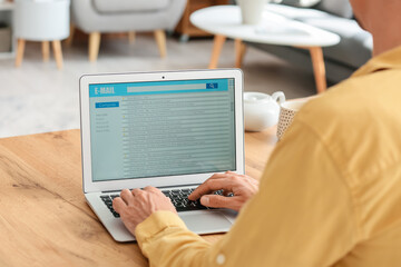 Young man with laptop checking his e-mail at home
