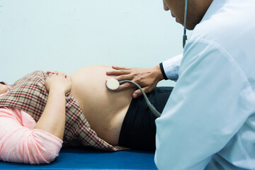 Doctor using stethoscope examining pregnant woman in the hospital.Medical exam new born concept.Obstetric Clinic