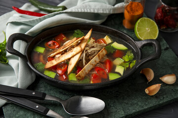 Baking dish with tasty Sopa de Lima soup on table