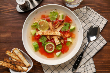 Plate of tasty Sopa de Lima soup on wooden background