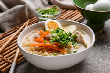 Tasty Chinese soup with chicken in bowl on grunge background