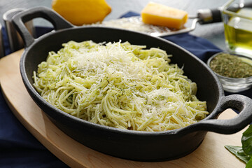 frying pan with tasty pesto pasta on table, closeup