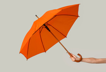 Female hand with open umbrella on light background
