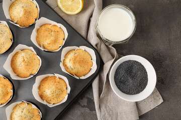 Baking tin with poppy seed muffins on table