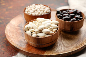 Bowls with different types of beans on grunge background