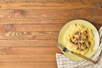 Plate with tasty mashed potatoes and mushrooms on wooden background
