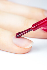Obraz na płótnie Canvas Woman applies red nail polish..Girl making a manicure. Salon procedures at home. Beautiful hands and nails. Close up, macro photo.