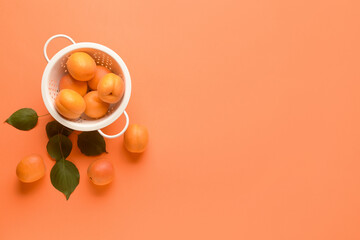 Obraz na płótnie Canvas Colander with tasty ripe apricots on color background