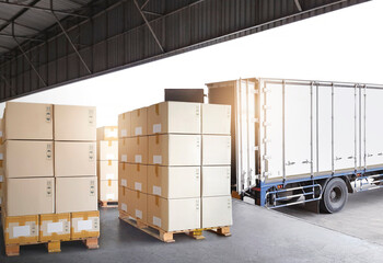 Packaging Boxes Stacked on Pallets Loading with Shipping Cargo Container. Truck Parked Loading at...