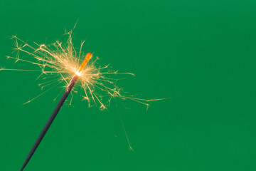 Burning firework sparkler on green background 