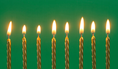 Golden birthday candles on green background