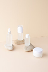 Cosmetic skin care products with stones on pastel beige background. Close up, copy space