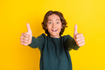 Portrait of attractive cheerful boy giving you two thumbup great solution isolated over bright yellow color background