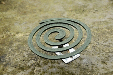 closeup the green mosquito coil with metal stand over out of focus brown background.