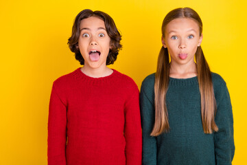 Portrait of attractive funny cheerful trendy couple grimacing fooling isolated over bright yellow...