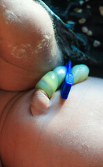 The umbilical cord of a newborn baby with a clothespin on the tummy. Asian newborn with umbilical cord attached to clip. Sleepy infant after breastfeeding.