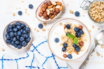Yogurt granola with fresh blueberries on white wooden table. Top view with copy space. Healthy food, snack or breakfast.
