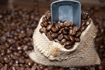Dark roasted coffee beans with scoop on wooden background