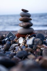 Fototapeta na wymiar Balances Stones on the Rocky Beach with Sea Background