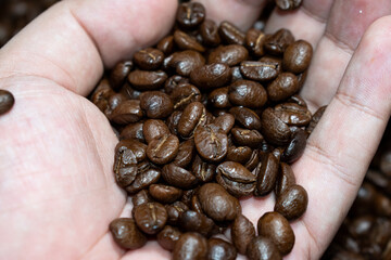 Coffee beans in hands on dark background