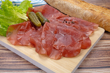 tranches de bresaola sur une planche à découper	