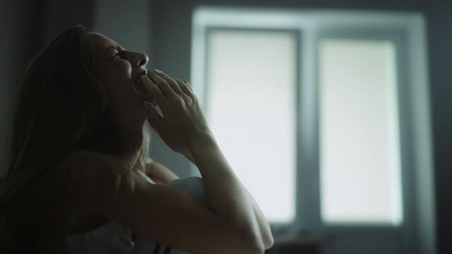 A headache woman is crying and feeling tired, lonely and unhappy at home. Stressed girl is thinking of personal or health problems and suffering from depression or worrying about wrong decision.