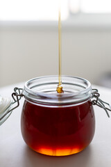 fresh natural buckwheat honey is poured into a jar